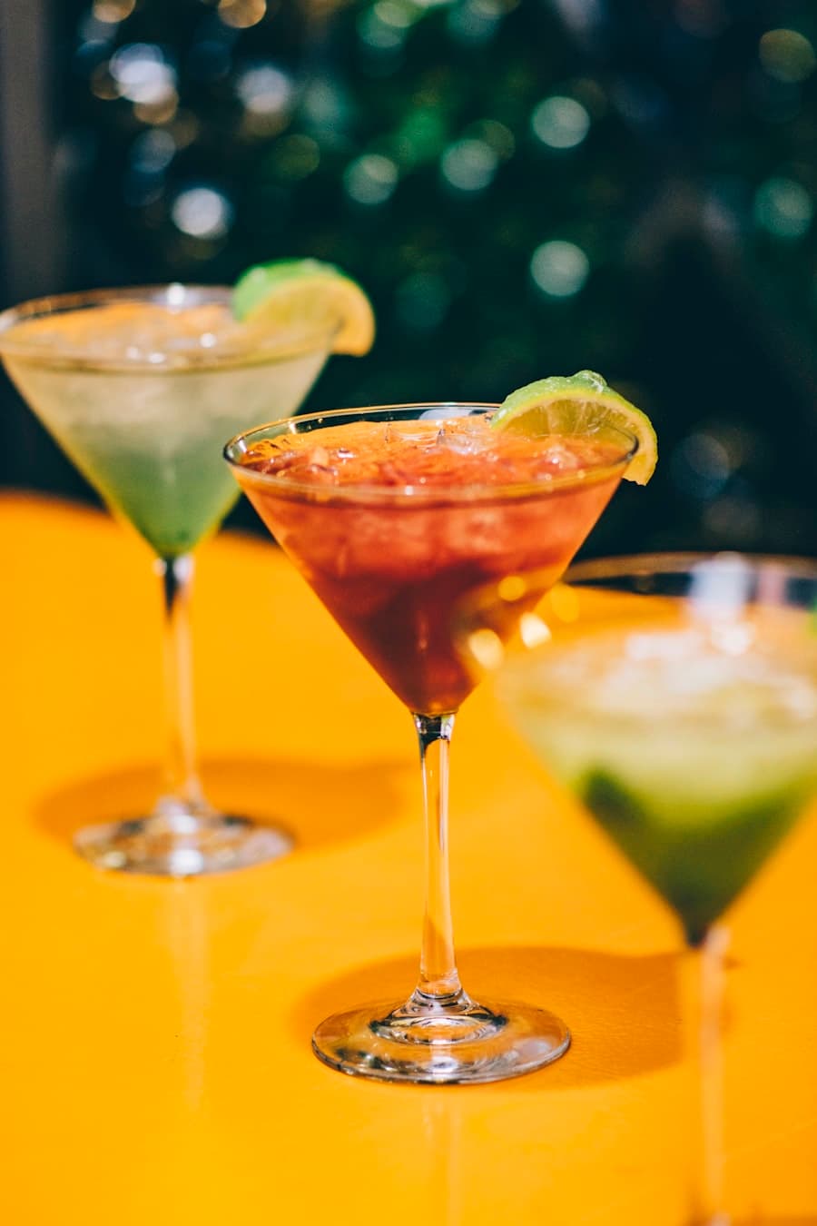 Trois cocktails colorés en verres à martini sur une table dorée
