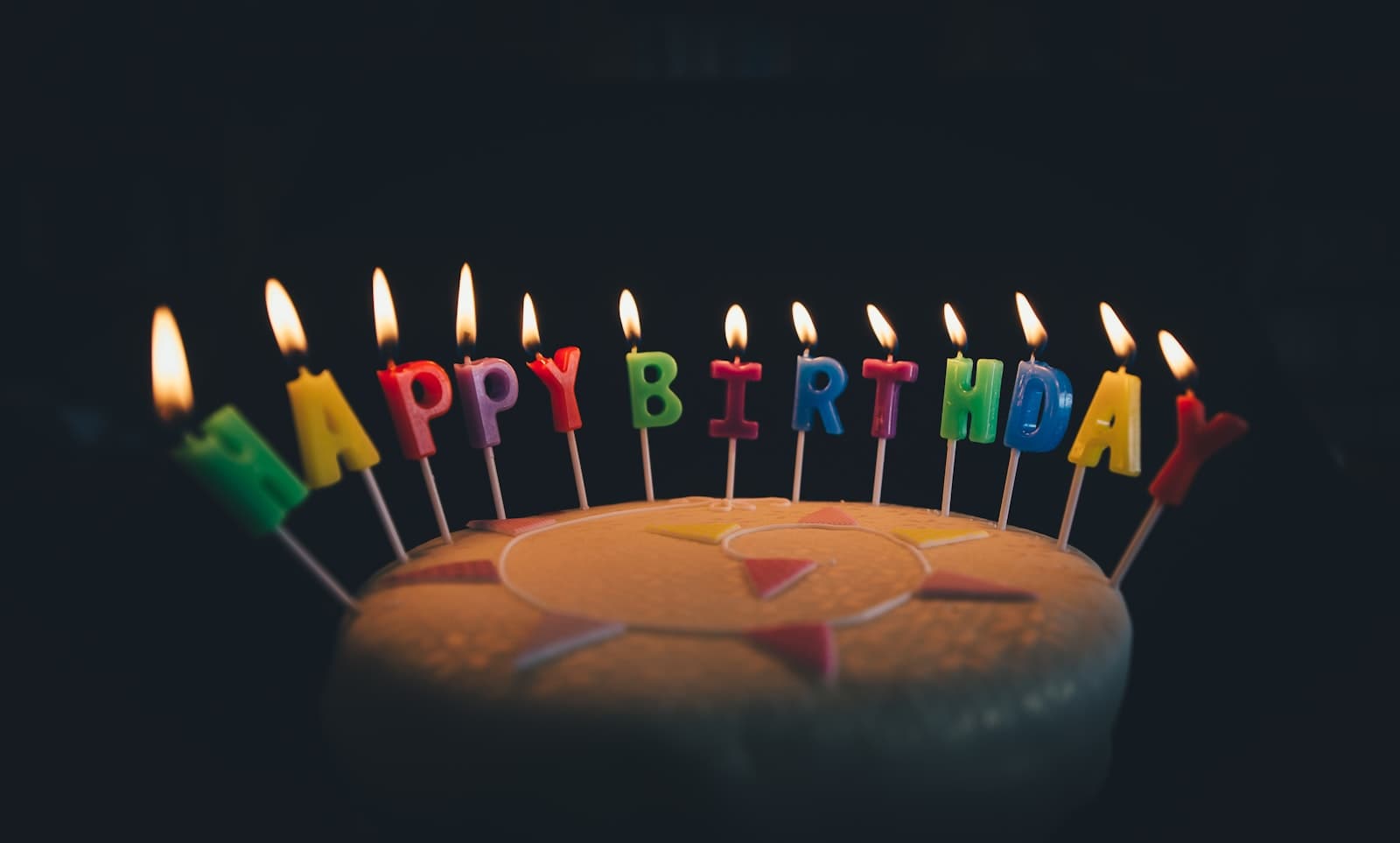 Gâteau d'anniversaire aux bougies multicolores allumées dans la pénombre