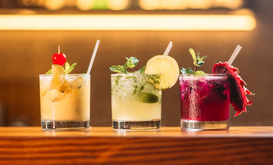 Trois cocktails frais garnis de menthe et d'agrumes sur le comptoir